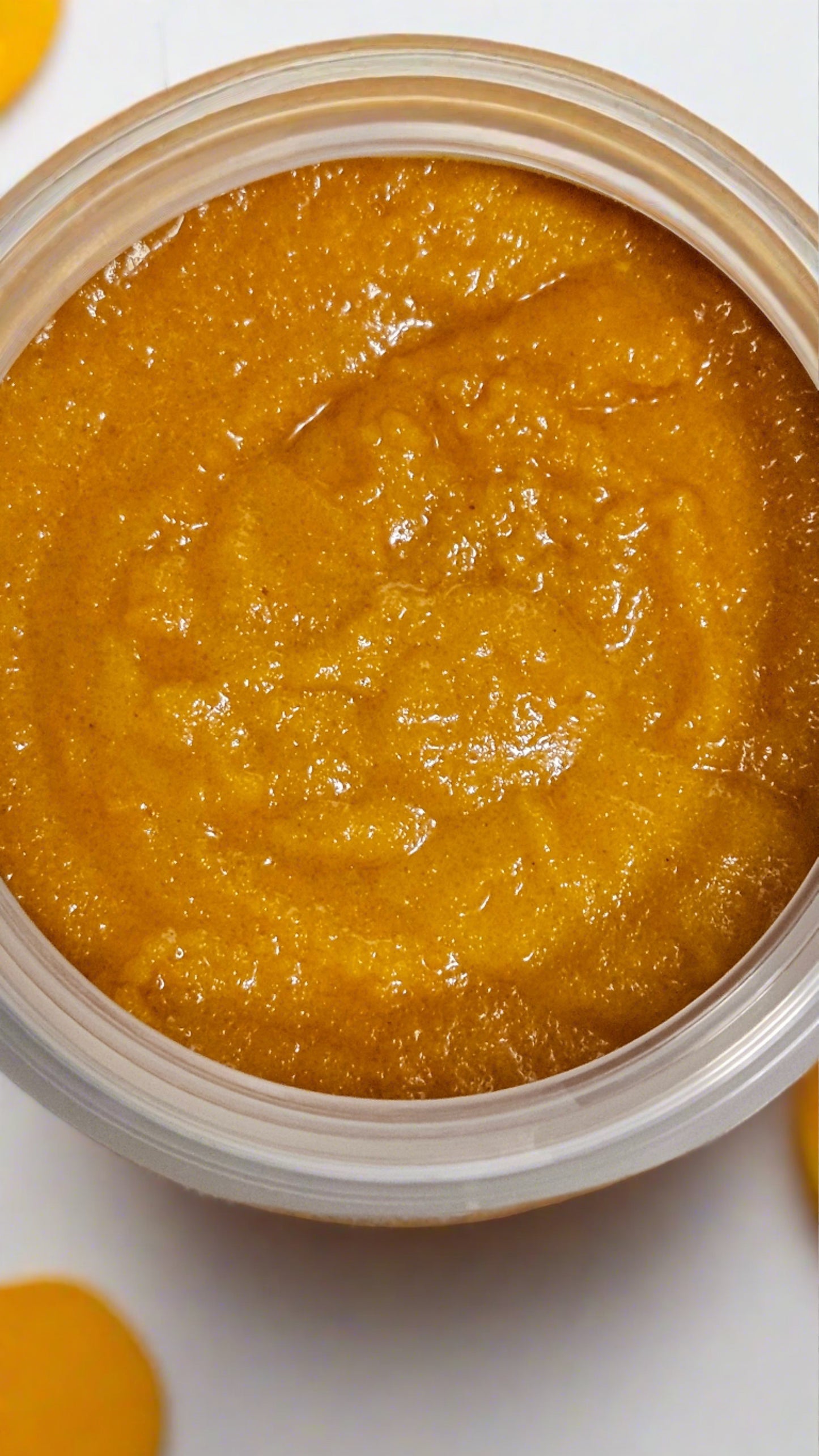 Top view of an open jar showing orange colored contents of Mango & Sugar Exfoliating Body Scrub - Clarifying Turmeric